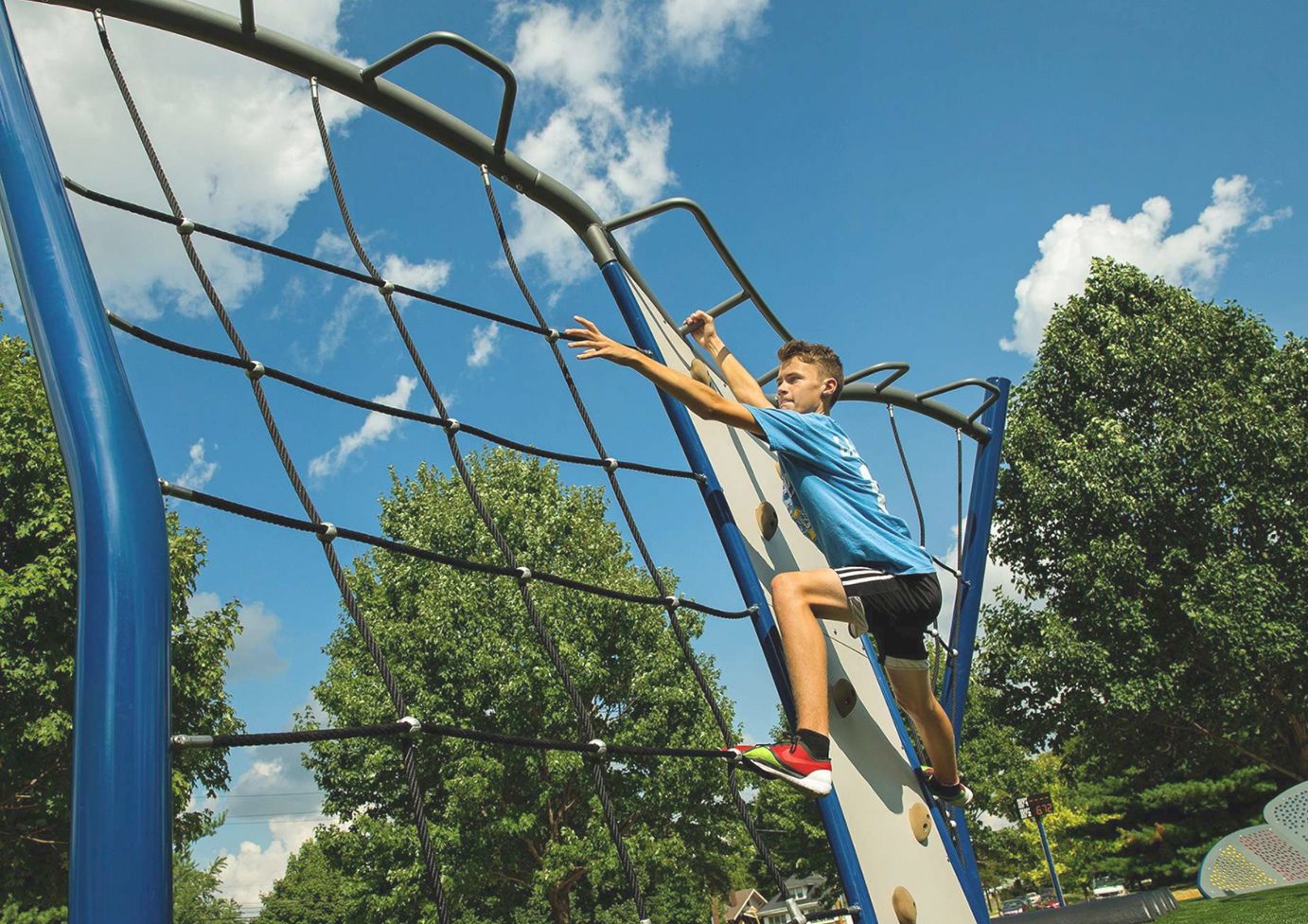 Boy scaling outdoor climbing equipment