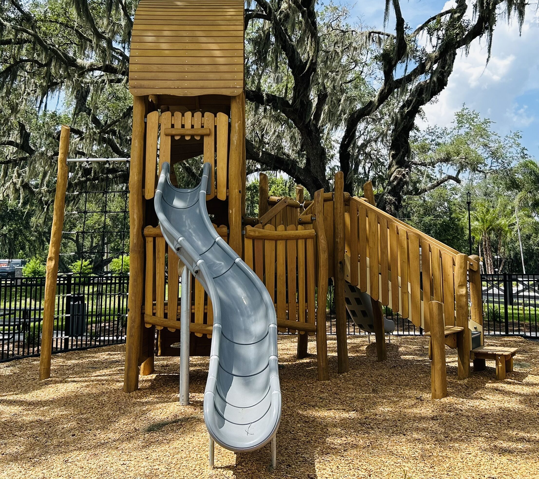 Wooden playground with slide and climbing steps.