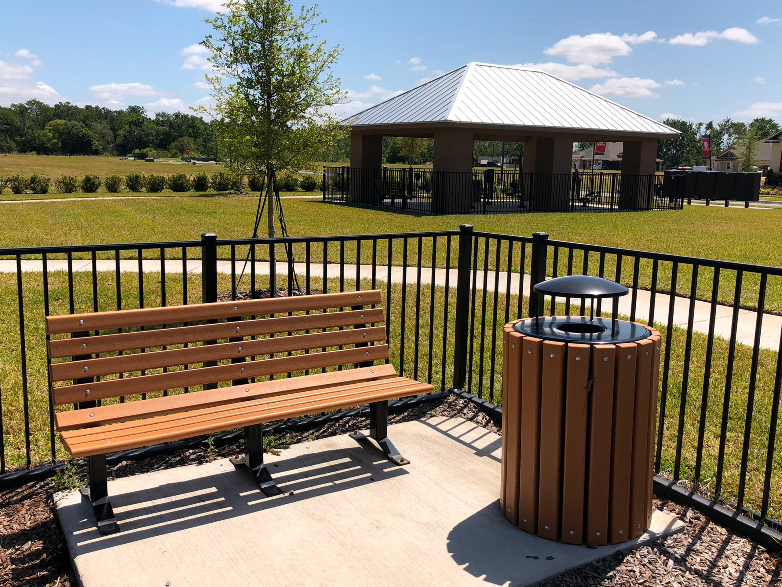Park bench and trash can in sun