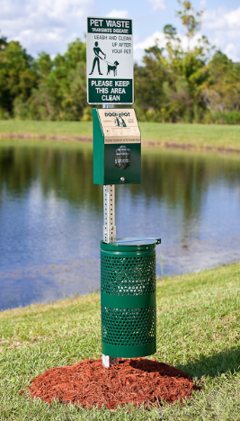 Green pet waste receptacle near water