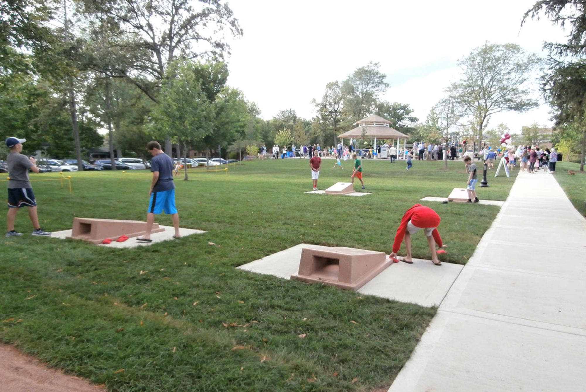 Families enjoying cornhole in green space